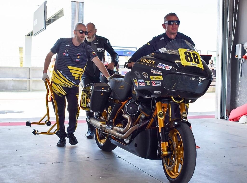 Three members of the LORD’S Racing Team pushing Harley-Davidson BEE #88 into the paddock after a BRL European Cup session at Cremona Circuit.