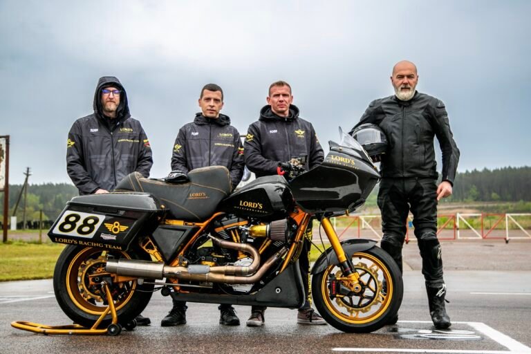 LORD’S Racing Team standing next to the HD LORD’S BEE performance bagger at Nemuno Žiedas racetrack during a rainy training day.